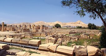 <p>The ruins of the audience hall are marked by the partially restored columns visible to the left. Although the mosaics were covered for conservation until a permanent, protective shelter can be built over them, excavations, research and conservation continue at other locations amid the palace, mosques, baths, residences and agricultural estate at Khirbat al-Mafjar.</p>
