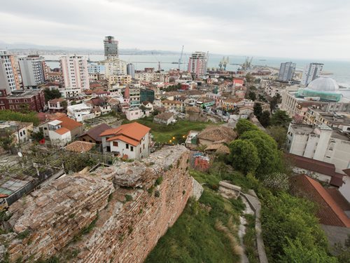 <em>Top:</em> Women stroll the waterfront in Durrës, Albania, western terminus of the Via Egnatia and today the country&#39;s leading port. <em>Above: </em>Homes in Durrës stand amid ruins overlooking the Strait of Otranto on the Adriatic Sea. Seventy-two kilometers over the water lies Brindisi, Italy, the southern terminus of the Via Appia to Rome.