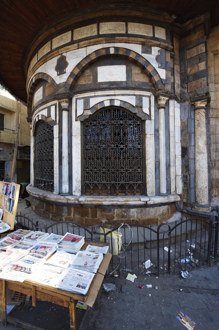 Marble veneer carved with arabesque and lintels of stone in alternating colors frame the three large, grilled windows of the <em>sabil</em>, or public fountain, of Mustafa III. His tugra, or official calligraphic seal, is set above each window. Of the more than 300 <em>sabil-kuttabs</em> that once existed in Cairo, today about 70 remain.