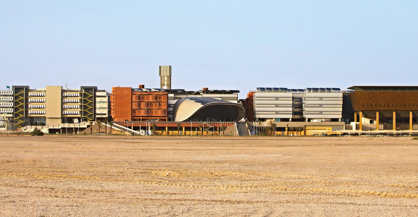 <p>With its wind tower playing an iconic role not unlike a central skyscraper in a more conventional city, Masdar City limits its building height to five stories to maximize energy efficiency. The original platform separating the transportation-oriented lower level can be seen below the buildings, center. The master plan calls for a green corridor, now under construction, along this strip of sand.</p>