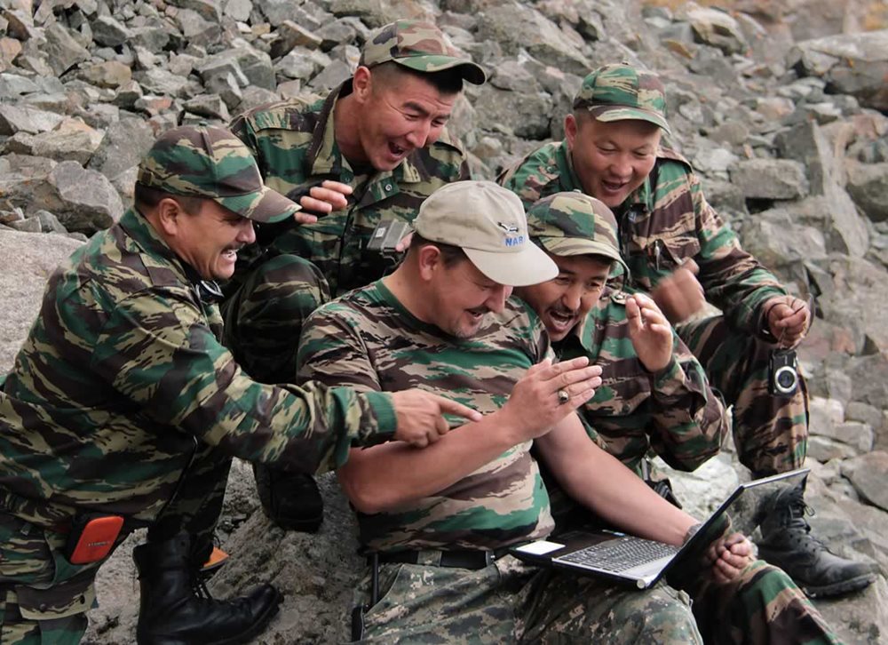 Reacting with delight to camera-trap photographs recovered from the field, a team of conservationists examines digital files on location in Chon-Kemin National Park in Kyrgyzstan.