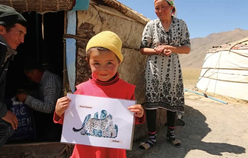 In Tajikistan&rsquo;s Akhtam Valley, a child holds up an illustration of a snow leopard that was part of an educational effort to assist residents living in shared habitat to protect both the species and their own livelihoods.