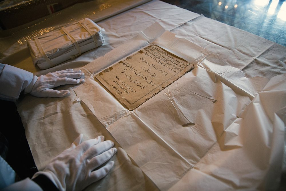 Working to piece together histories denied during apartheid, Fatima February of the Iziko Social History Centre in Cape Town shows a kitab that is being conserved in an archival wrap and box.