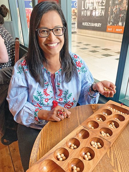 Geraldine Pinto, who grew up in Malaysia, gets her congkak board ready in a cafe in Banbury, England. 