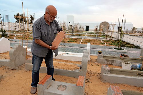 Koraïchi places a plaque on a grave site.