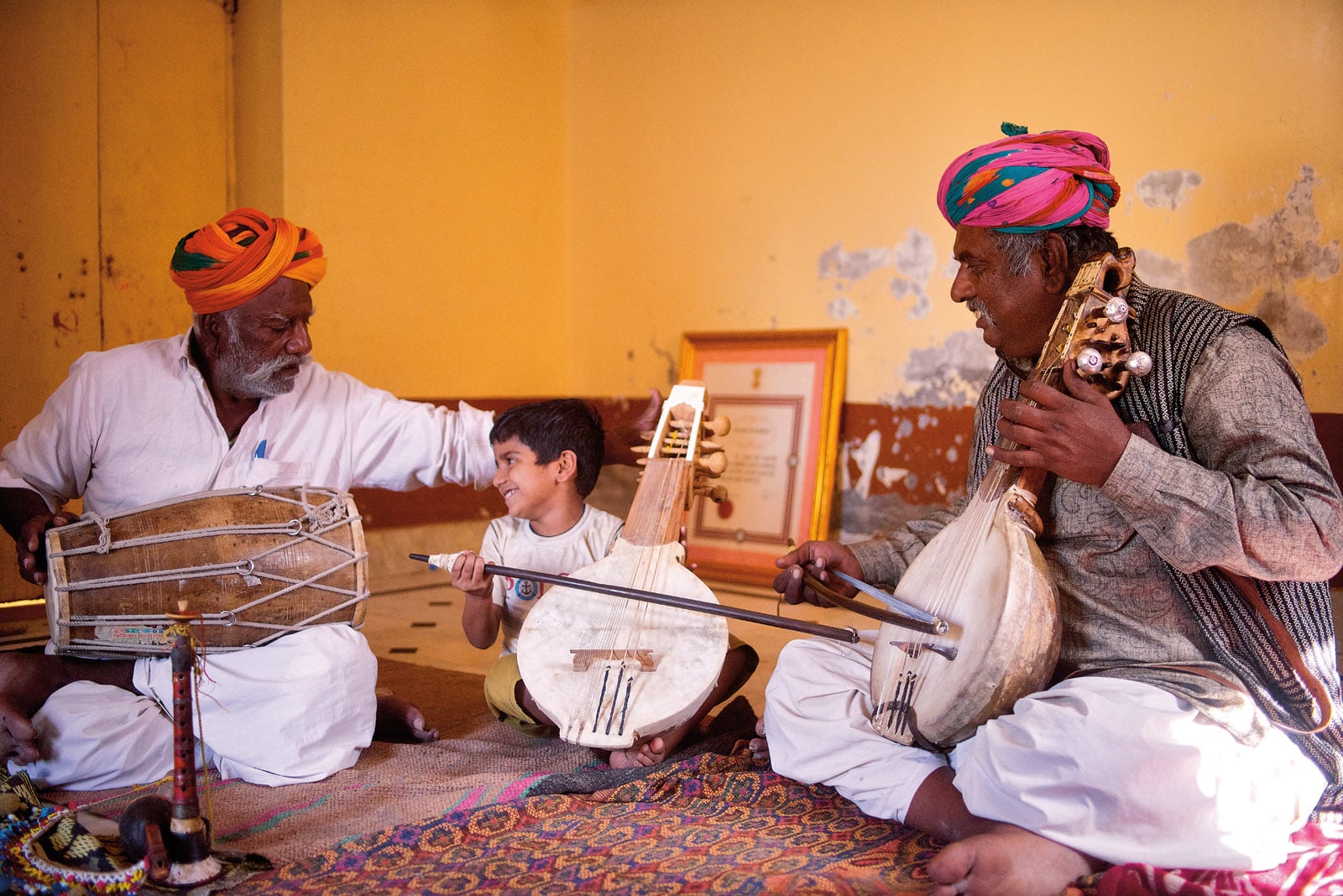 Learning his family traditions, Ayan Khan Manganiyar, 5, plays the kamaicha and gets some help from his great-great-uncle Pempe Khan Manganiyar, left, as his grandfather Ghewar Khan Manganiyar, right, plays along.