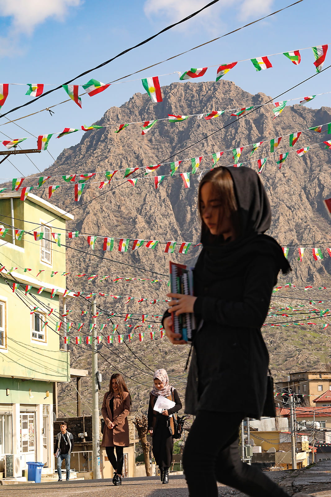 Mountains tower over students walking to school in Amedi. Space is at a premium in the one-square-kilometer city, making the preservation of historic sites a challenge in the face of ongoing development.