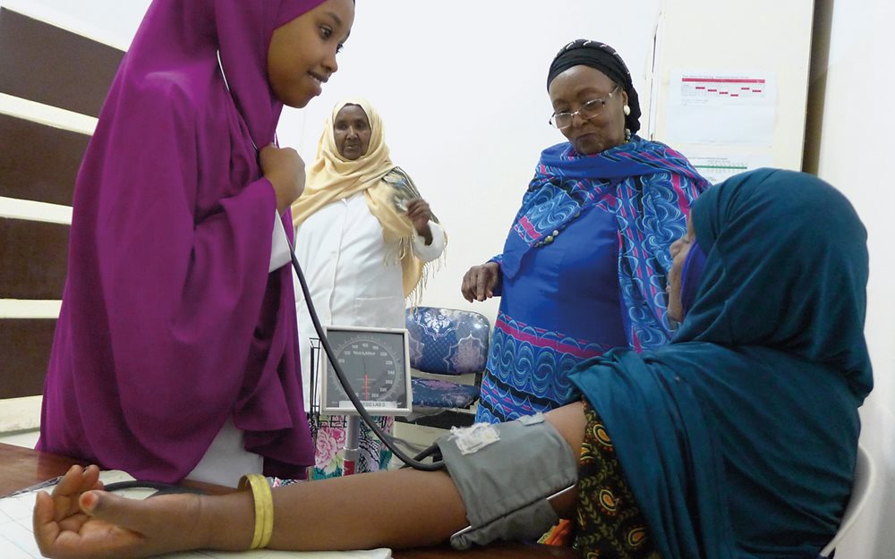 With Adan looking on together with outpatient department head Asha Farah, third-year nursing student Najah Ahmed Mohamed takes a patient&rsquo;s blood pressure. To build the hospital that opened in 2002, Adan sold her home and donated her pension from 30 years of work with the World Health Organization.